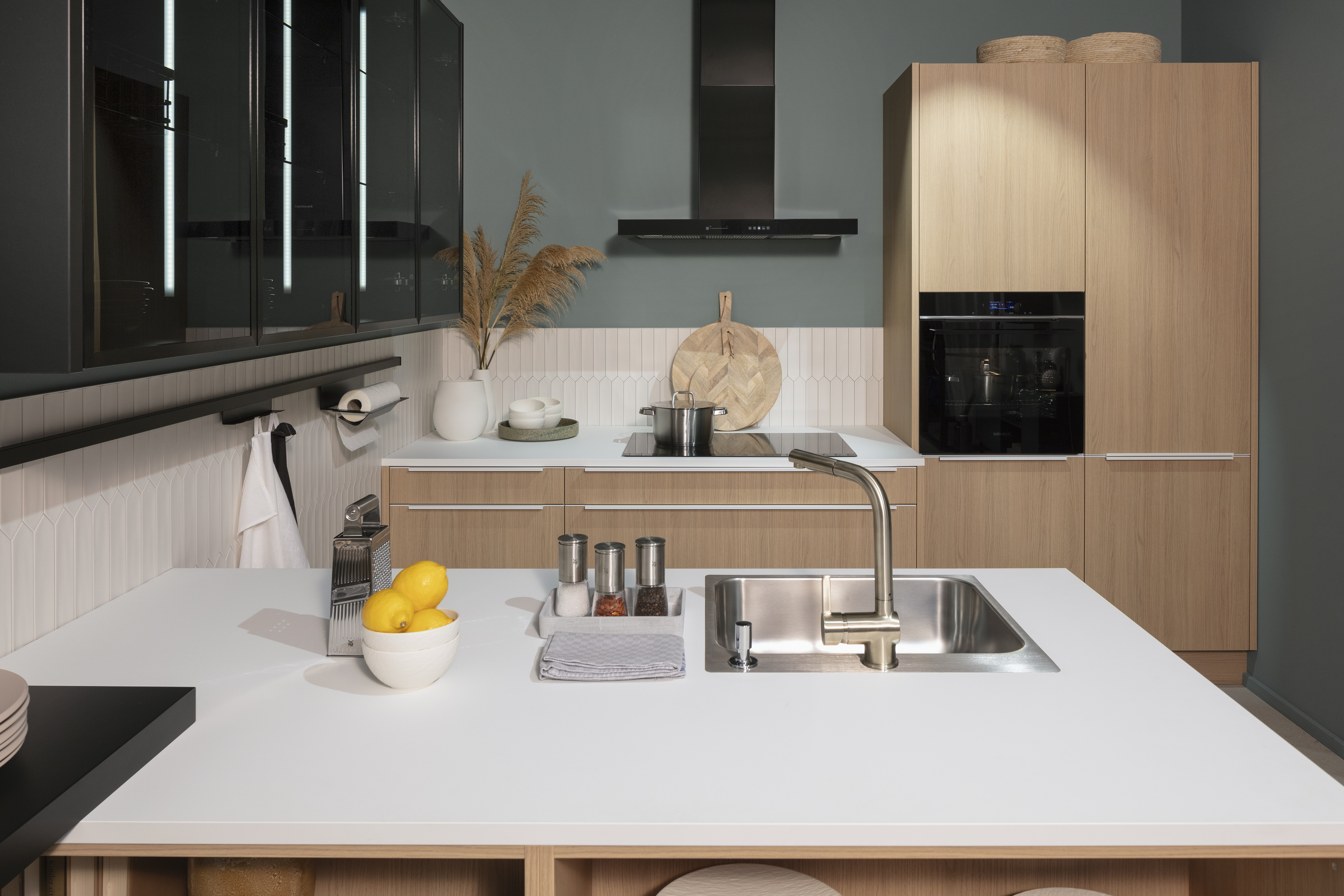 Kücheninsel mit Kristallweißer Arbeitsplatte und Küchenzeile im Hintergrund. 