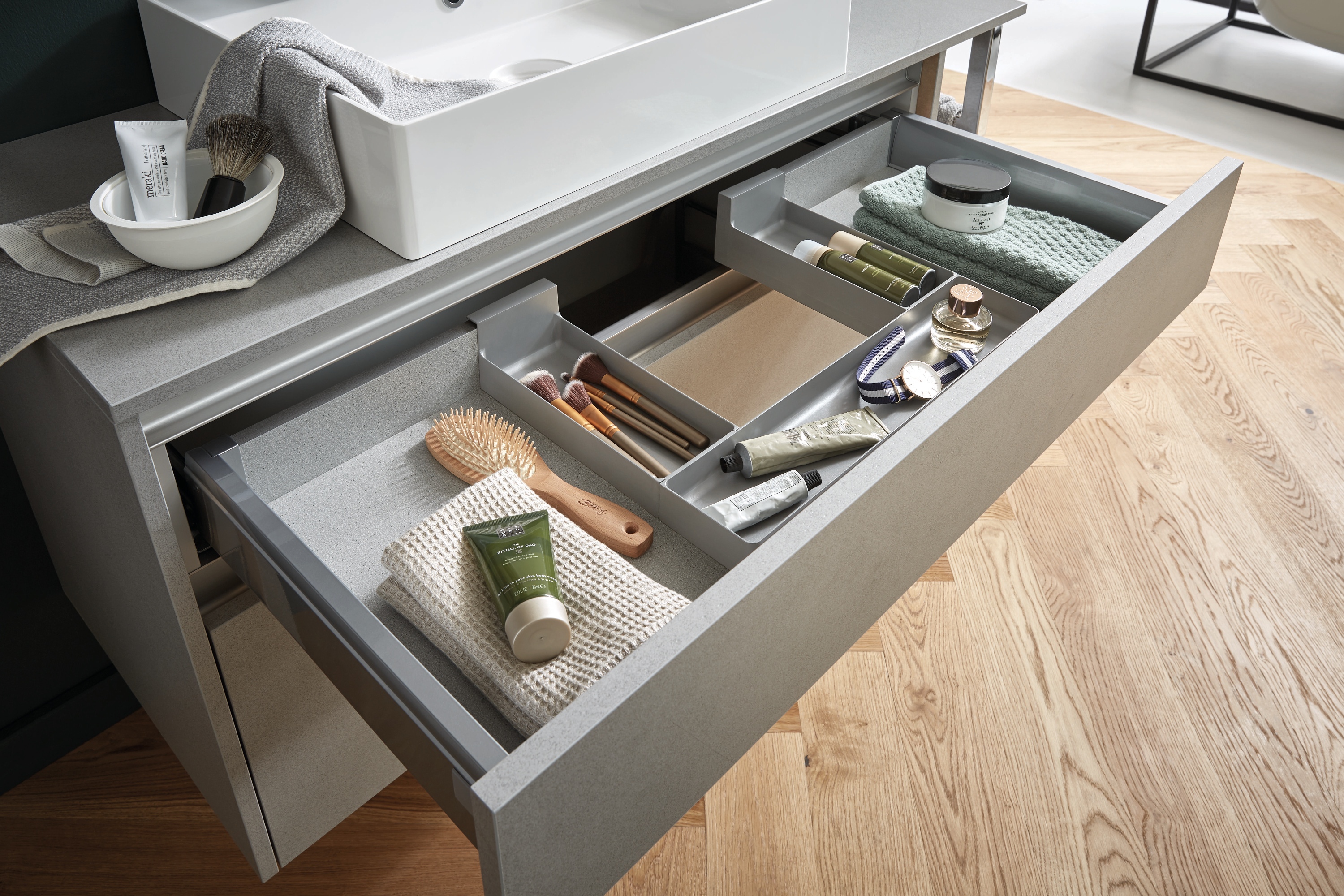 Detailansicht von einem Auszug unter dem Waschbecken mit einer Einteilung für Badezimmerutensilien